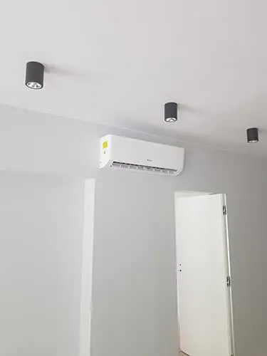 Klimatyzator ścienny nad drzwiami w jasnym pokoju